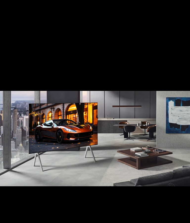 Dzīvojamā istaba ar LG True Wireless TV uz statīva. Zero Connect Box zem sānu galdiņa pie dīvāna gandrīz nevar saskatīt, parādot, ka to var ērti novietot jebkur. Viss istabas izkārtojums ir skaits un kārtīgs.