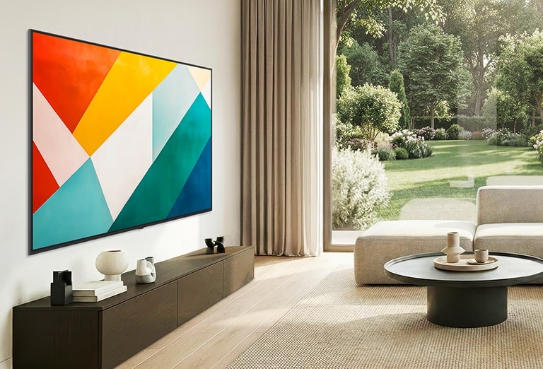 LG QNED evo AI QNED85 Mini LED ar Super Slim Design tehnoloģiju piestiprināts pie sienas gaišā, atvērtā tipa dzīvojamā telpā un saplūst ar interjeru, ekrānā rādot izteiktu ģeometrisku abstraktu mākslas darbu.