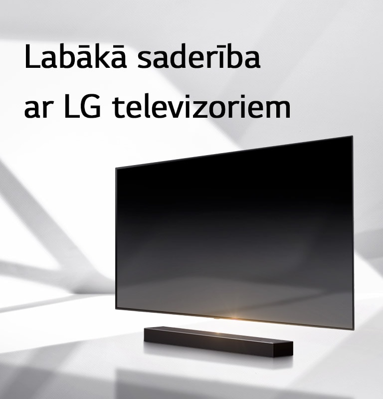 Skaņas josla un televizors novietoti uz baltas grīdas, un no ārpuses aiz tiem stiepjas ēna.