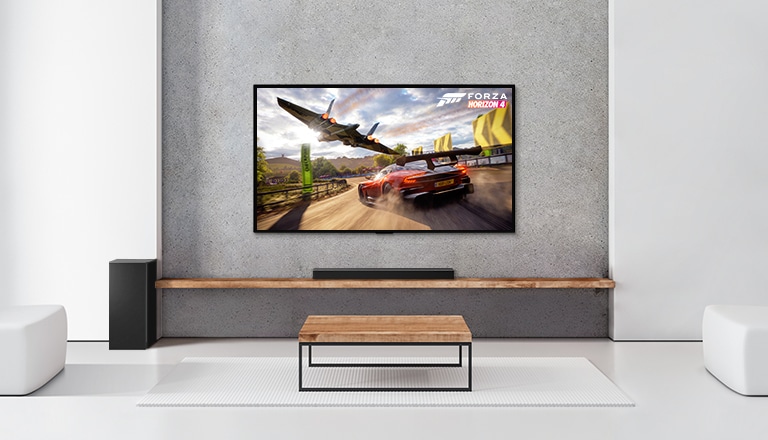 Baltā viesistabā redzami divi aizmugures skaļruņi, zemo frekvenču pastiprinātājs, skaņas josla un televizors. Televizora ekrānā redzama braucoša automašīna un kosmosa kuģis.