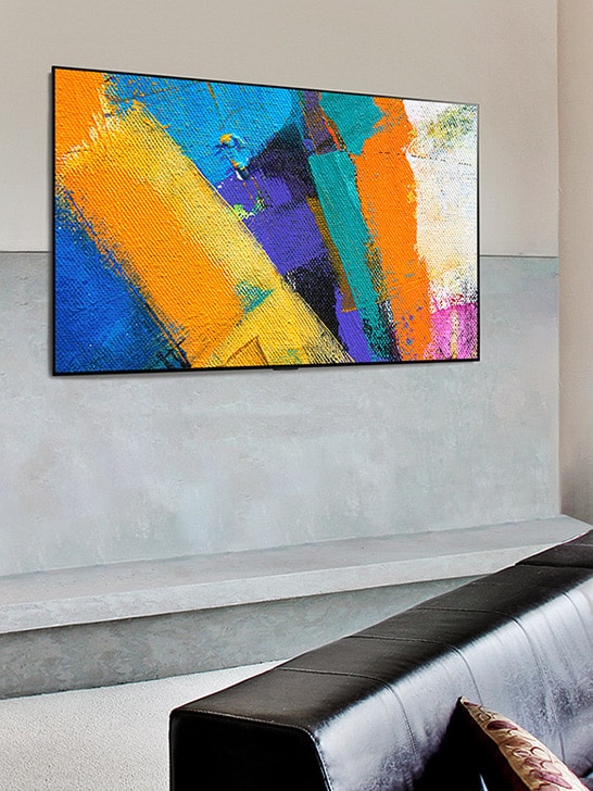 Attēls ar pie sienas piestiprinātu Gallery Design televizoru, kurā redzams mākslas darbs viesistabā.