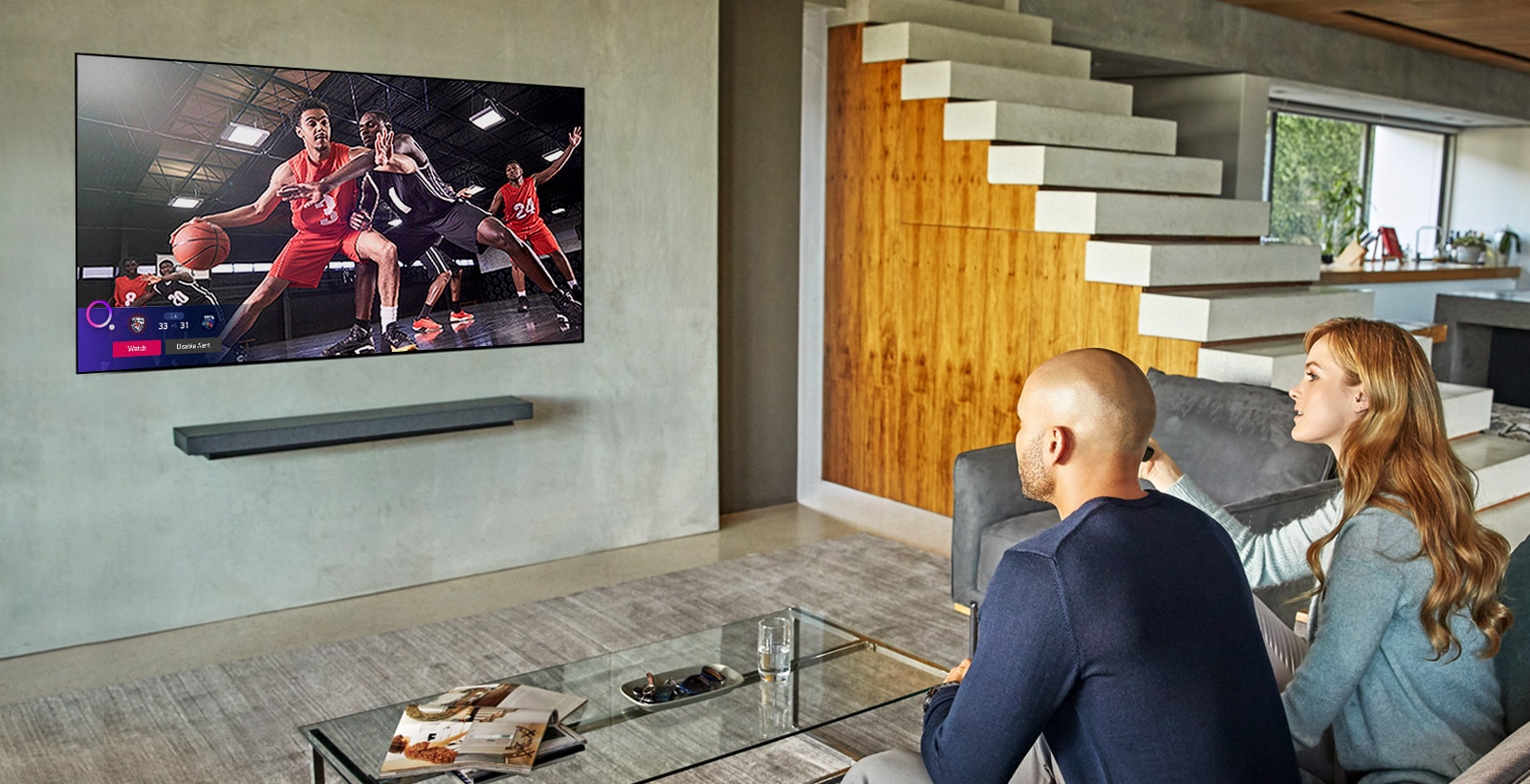 Pārītis dīvānā televizorā skatās basketbola spēli