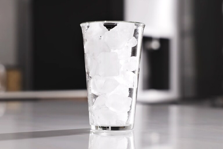 Caurspīdīga glāze, kas pildīta ar kvadrātiskiem ledus kubiņiem no LG ledusskapja
