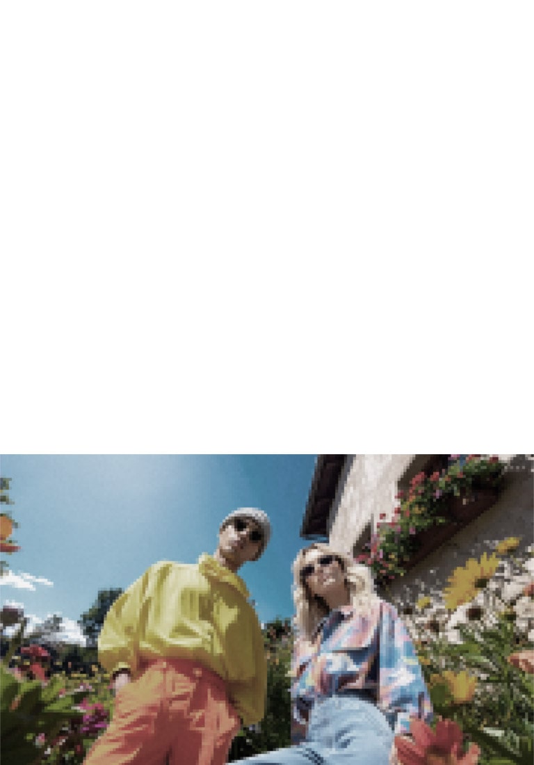 LG QNED evo AI QNED82 Mini LED ar AI Picture Pro rāda zema leņķa āra dzīvesveida ainu ar diviem cilvēkiem starp dzīvīgiem ziediem, kamēr mākslīgais intelekts atpazīst un uzlabo katru kadru līdz 4K skaidrākai tekstūrai un detaļām.