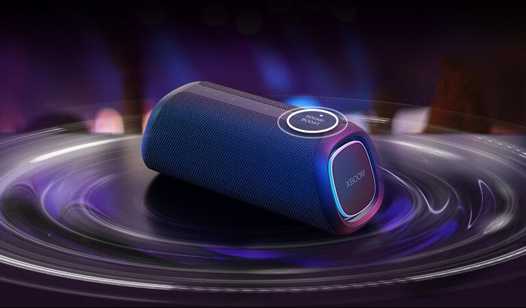 LG XBOOM GO XG5 ir novietots uz galda. Poga Sound Boost ir palielināta, un skaņas viļņu efekti atrodas zem skaļruņa. Atskaņojiet video.