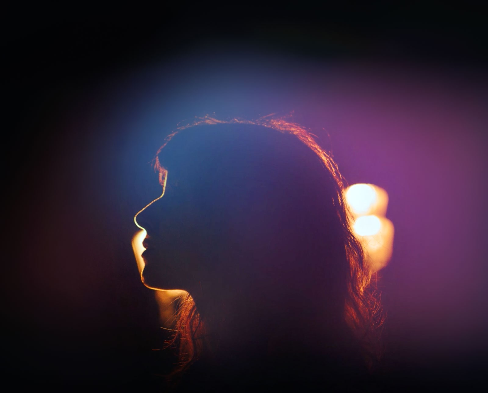 Violetā gaisma apspīd sievietes siluetu.