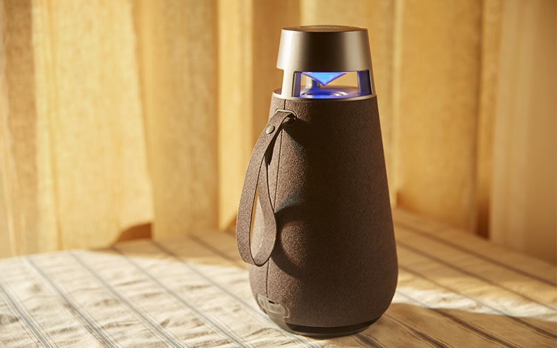 Attēls ar XBOOM 360 XO3, parādot noņemamo auduma siksniņu.