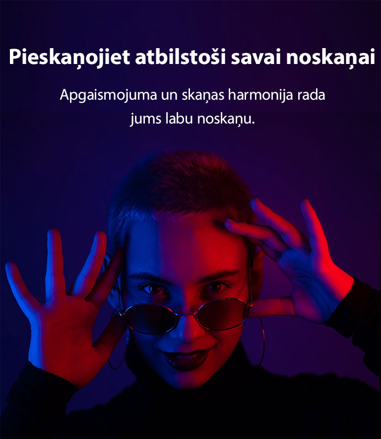 Sieviete pozē spilgtā apgaismojumā.