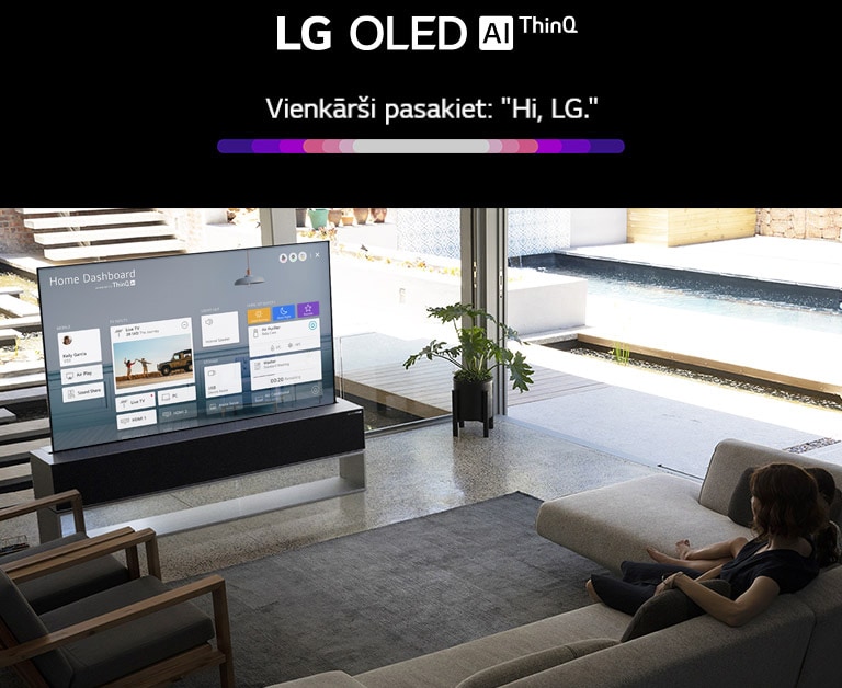 Māte ar meitu sēž uz dīvāna viesistabā, un televizora ekrānā redzams mājas informācijas panelis