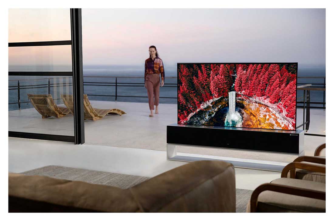 LG 65 collu OLED 4K televizors, A living room with a Rollable TV displaying a waterfall between maple trees, while a woman is walking inside from the terrace, OLED65RX9LA, thumbnail 11