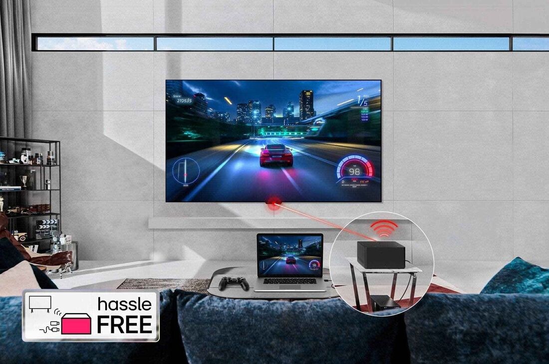 LG Pasaulē pirmais True Wireless TV 65 collu LG OLED evo AI M4 ar 4K 144Hz video un audio pārsūtīšanu , LG OLED evo M4, kas piestiprināts pie viesistabas sienas, un priekšpusē klēpjdators uz galda, kurā redzama tā pati autosacīkšu spēle. Zero Connect Box tuvplāns uz mazāka galda, apakšā ir pievienota ko, OLED65M49LA, thumbnail 13