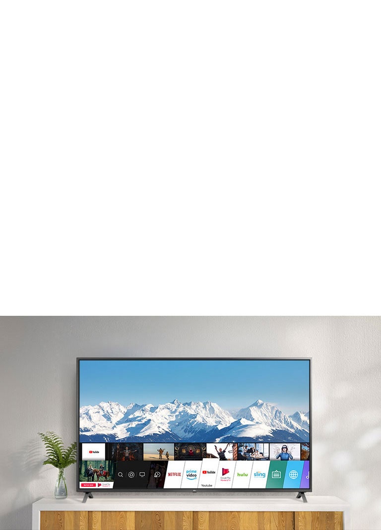 Téléviseur placé sur un support blanc contre un mur blanc. Écran de téléviseur montrant un écran d'accueil exécutant webOS.