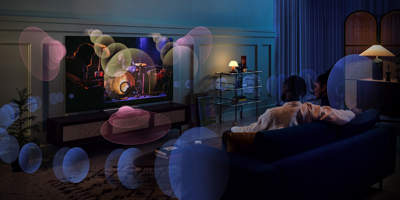 Una mujer está sentada en un sofá viendo un concierto con burbujas que representan un sonido envolvente a su alrededor.