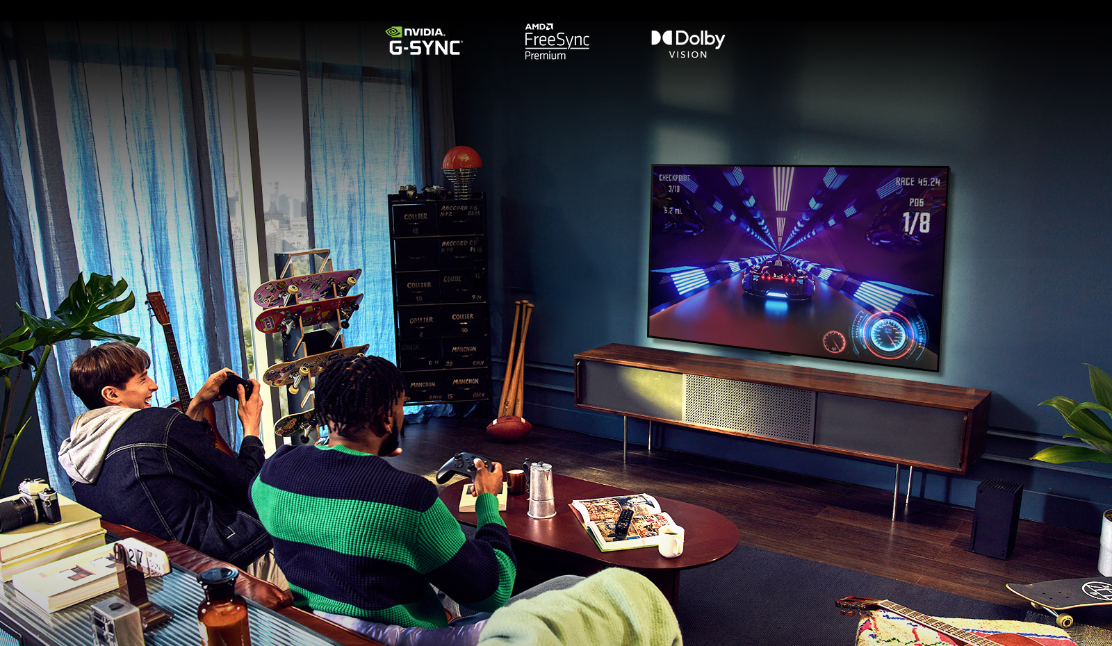 Dos personas sentadas en un sofá jugando a un juego de carreras con un mando y LG OLED G2 en un salón.