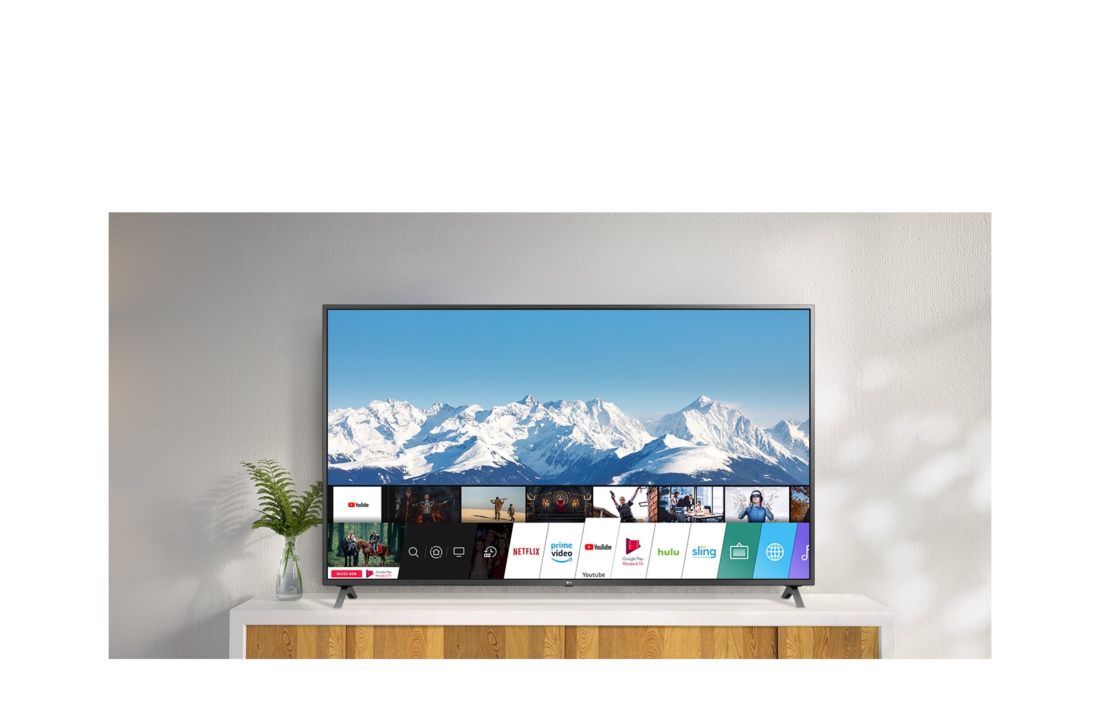 TV standing on a white stand against a white wall. TV screen shows home screen with webOS.