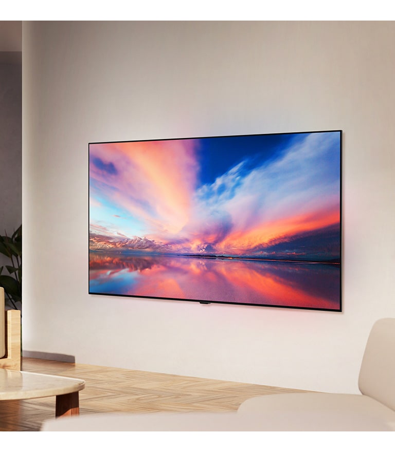 An image of LG OLED B4 on the wall of a neutral living space showing a colorful photo of a sunset over the ocean. 