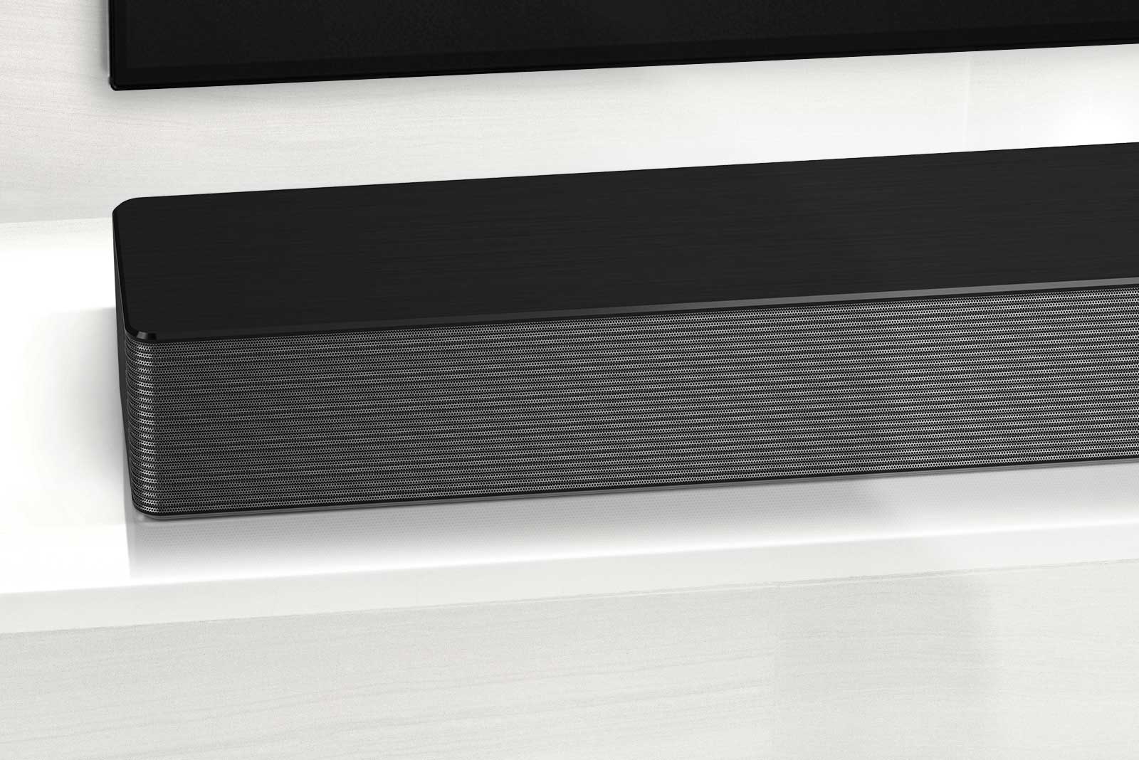 Close-up of LG Soundbar left corner. Bottom left side of TV is also visible. 