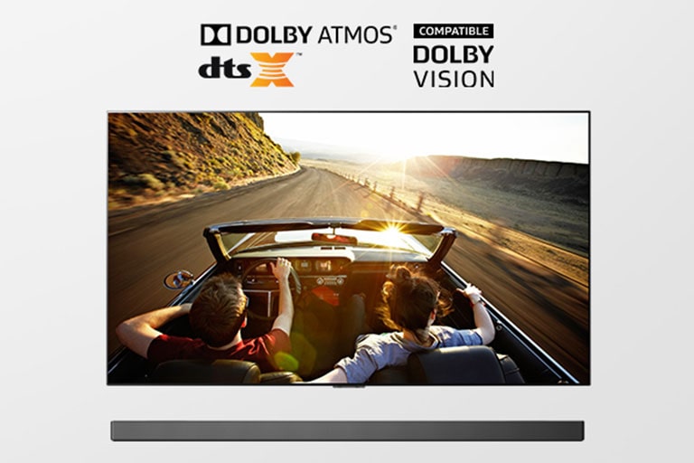 TV and Soundbar together in full view. TV shows a couple in an open roof car on the road driving into the sunset. 