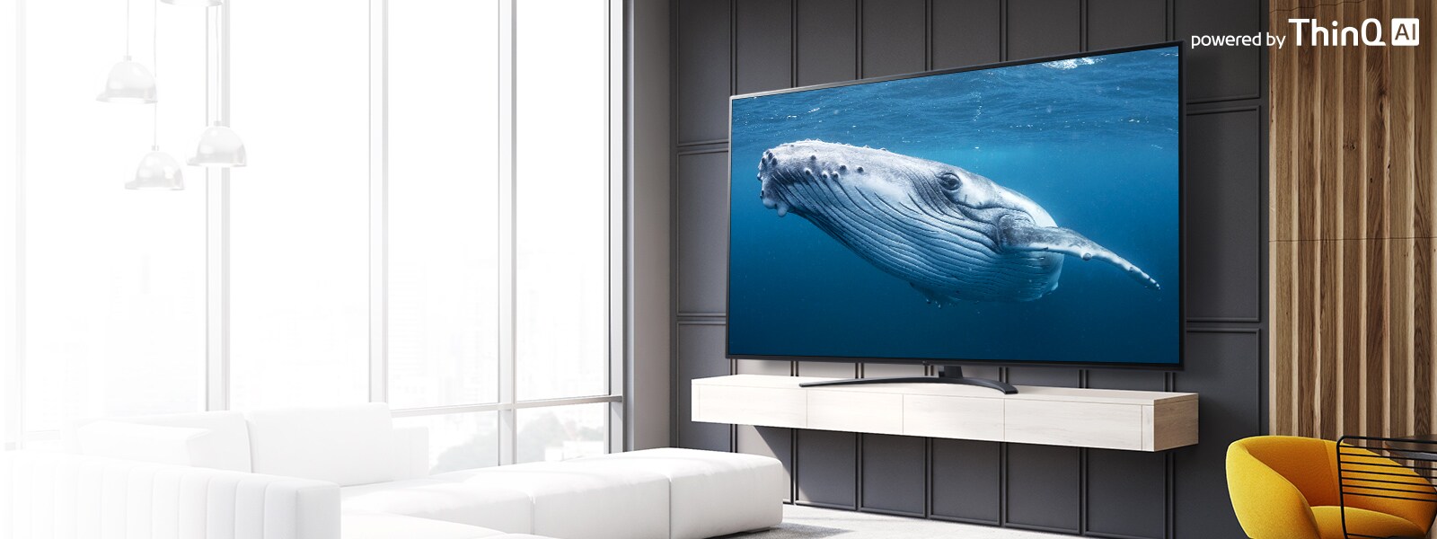 In a living room, there is a large screen TV displaying an image of a big whale in the sea. On the image, there is an introduction of a large screen TV on the left center and a powered by ThinQ AI logo on the upper right.