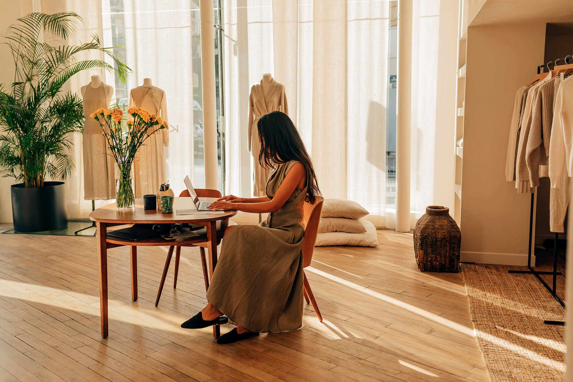 Bilde av Le Kasha-designer som setter seg foran et bord i et varmt opplyst atelier.