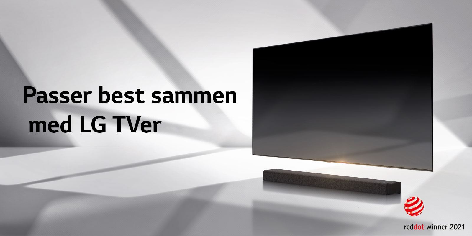 En lydplanke og en TV er plassert på et hvitt gulv og det er en skygge som kommer utenfra like bak.