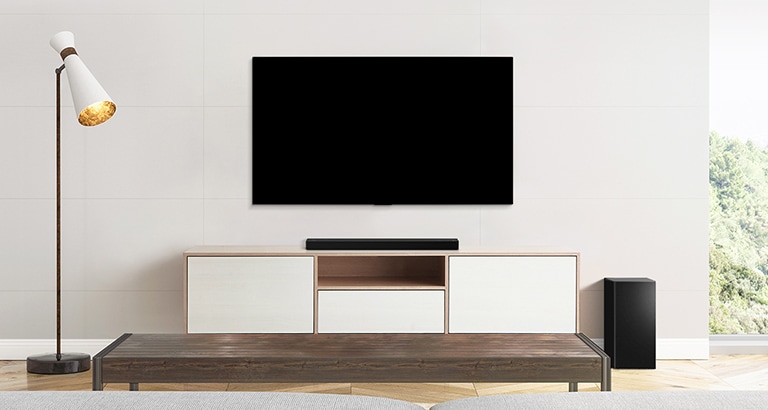 En TV, lydplanke og subwoofer plassert i en naken stue.