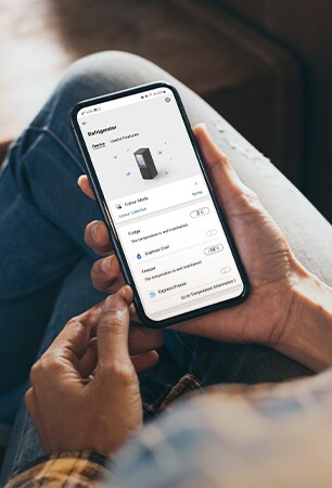 Bilde som viser en app som lar deg justere innstillinger i kjøleskapet direkte fra smarttelefonen som du holder i hånden.
