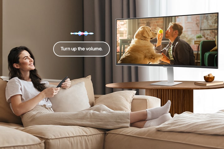 En kvinne skrur opp volumet på LG Smart Monitor med en Magic Remote.