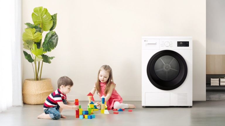 To barn som leker med fargerike klosser i nærheten av en tørketrommel