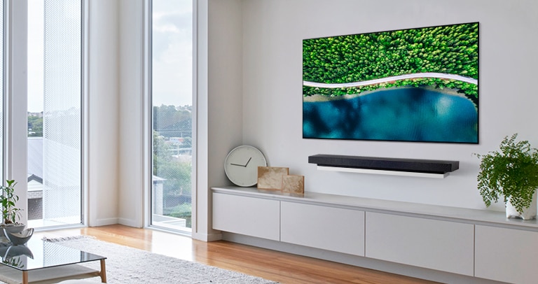 Stue med en grå stol og en TV med bilde av naturen i fugleperspektiv