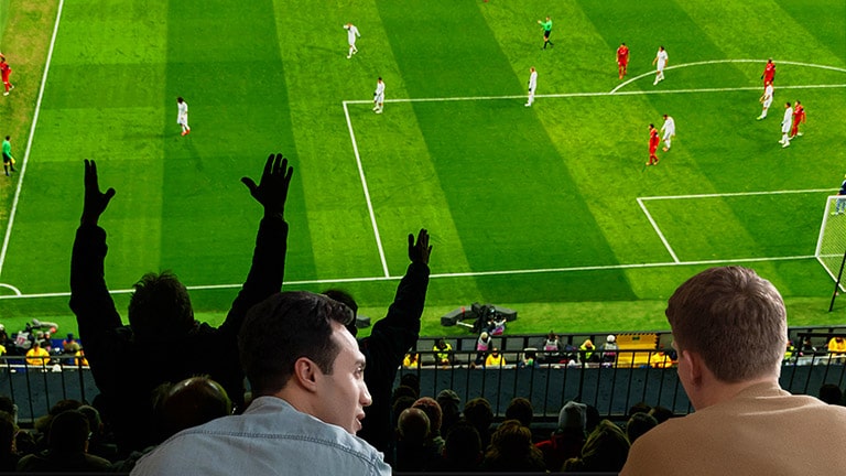 Folk som ser på en sportskamp på TV i stua med en ultrastor TV-skjerm