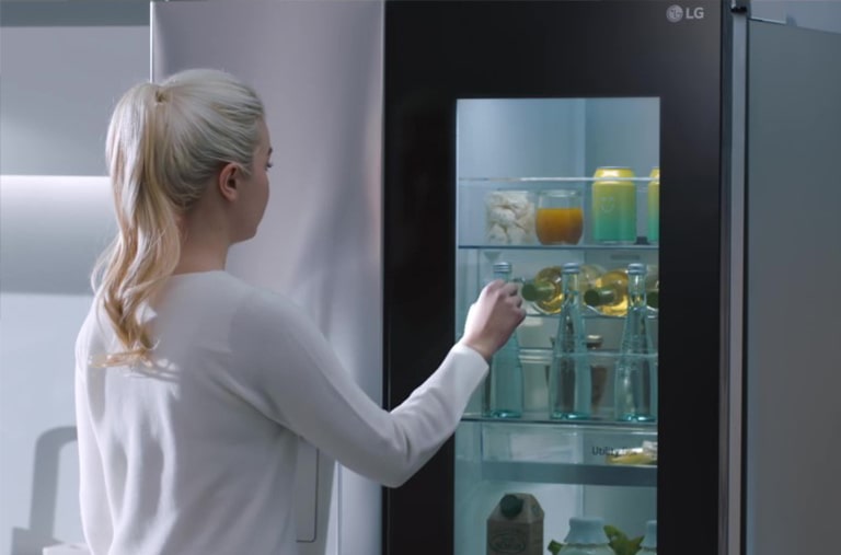 A video shows a woman approach her InstaView refrigerator and knock twice. The interior lights up and she can see the contents of her fridge without opening the door.