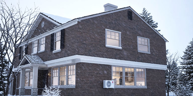 LG klimaanlegg for ekstremt kalde klima, med en utendørsenhet i snø og varm luftstrøm som fyller en koselig stue.