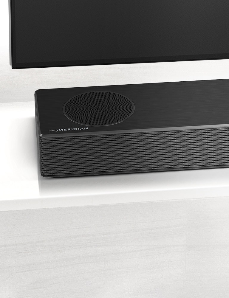 Nærbilde av LG Soundbars venstre side med Meridian-logoen vist på nedre venstre hjørne. Nedre venstre side av TVen er også synlig. 