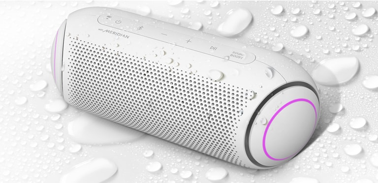 LG XBOOM Go er vendt opp mot venstre, mot en hvit bakgrunn. Det er vanndråper på og under LG XBOOM Go.