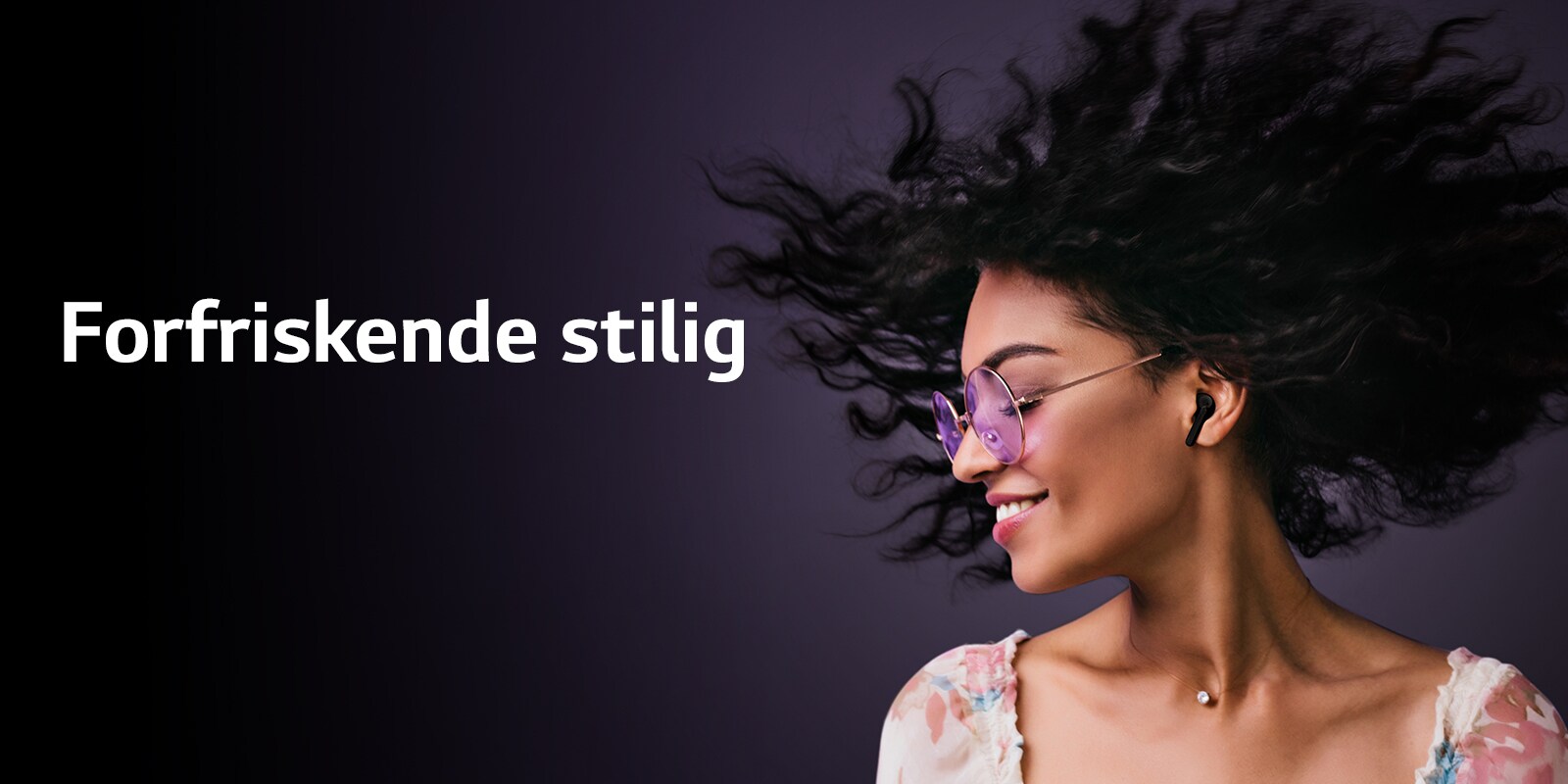 En kvinne smiler mens hun lytter til musikk med TONE Free.