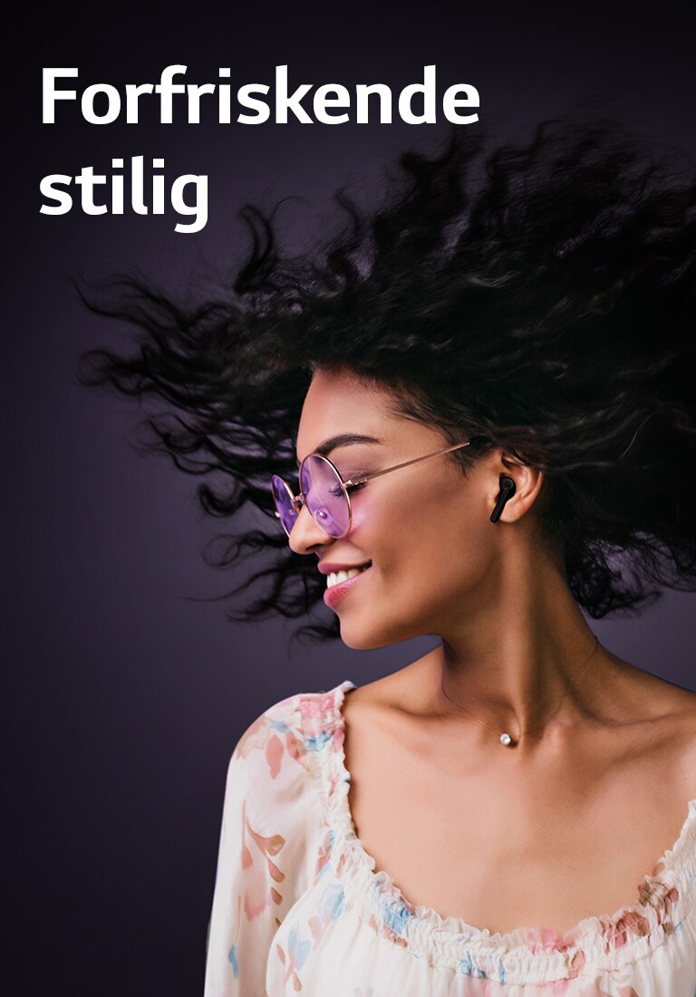 En kvinne smiler mens hun lytter til musikk med TONE Free.