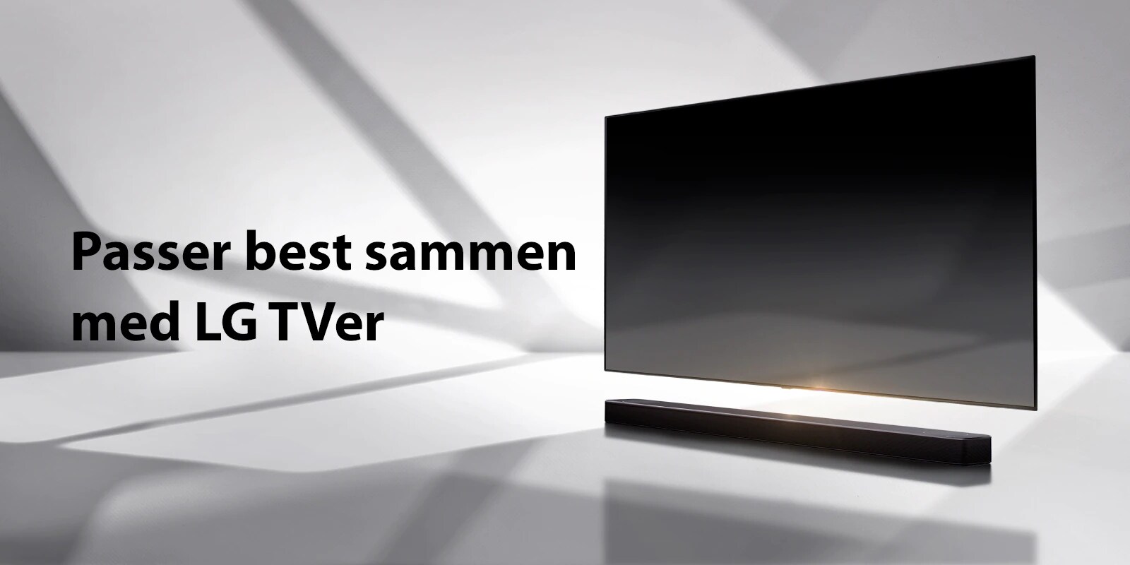 En lydplanke og en TV er plassert på et hvitt gulv og det er en skygge som kommer utenfra like bak.