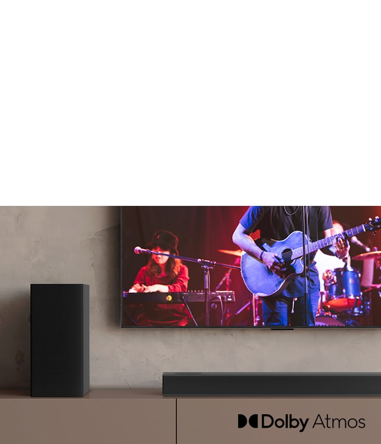 LG TV-en er plassert på den brune hyllen, LG Sound Bar S95QR er plassert foran TV-en. Subwooferen er plassert på venstre side av TV-en. TV-en viser en konsertscene. NYTT merke vises oppe i venstre hjørne.