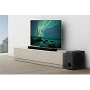 LG Soundbar S80QR, En lydplanke er plassert under en TV i en hvit stue, og subwooferen er plassert rett ved siden av., S80QR, thumbnail 5