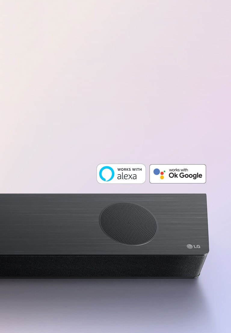 LG Sound Bar er plassert på bakken, og viser LG-logoen i høyre hjørne av lydplanken. Logoene Alexa og OK GOOGLE er plassert på lydplanken.