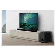 LG Soundbar S95QR, En lydplanke er plassert under en TV i en hvit stue, og subwooferen er plassert rett ved siden av., S95QR, thumbnail 5