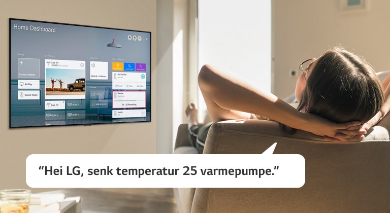 En kvinne ligger på en sofa mens hun ber TV-en om å senke temperaturen med startinstrumentpanelet på TV-skjermen
