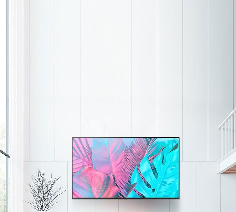 En stor veggfestet flatskjerm-TV mot en hvit vegg. Skjermen viser store blader i sterke farger.
