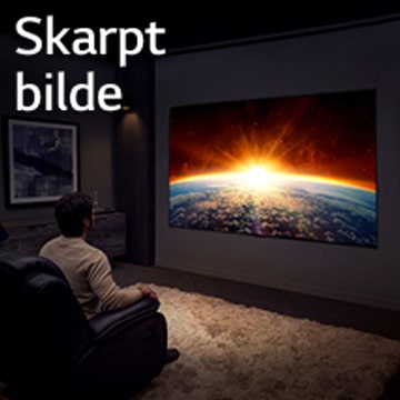 En mann sitter i en sofa i et mørkt rom og ser på TV som viser solen som går opp bak jorda.