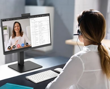 En kvinne med headset jobber mens hun ser på en skjerm.