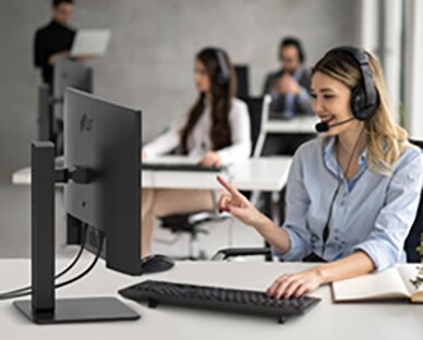 En kvinne med headset jobber mens hun ser på en skjerm.