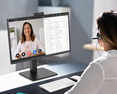 En kvinne med headset jobber mens hun ser på en skjerm.
