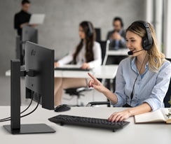 En kvinne med headset jobber mens hun ser på en skjerm.