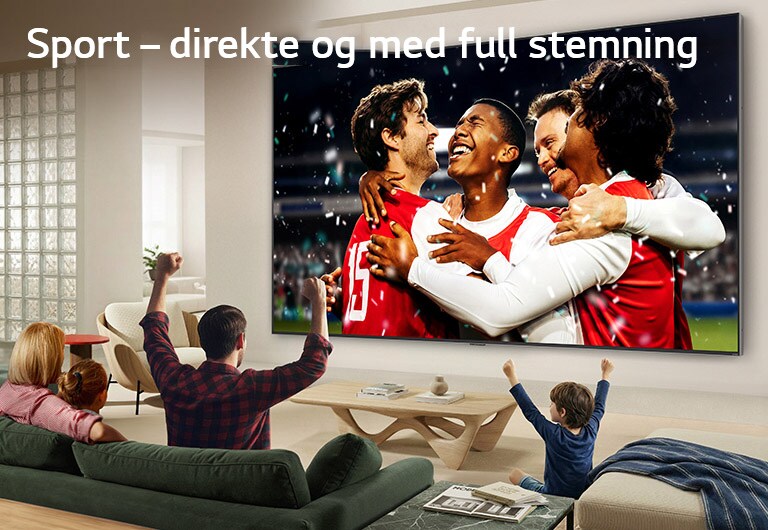 LG Ultra Big TV er veggmontert i en lys stue og viser en stadionfeiring med levende farger og raffinert bildekvalitet på en bred skjerm, mens en familie sitter i sofaen og heier sammen.